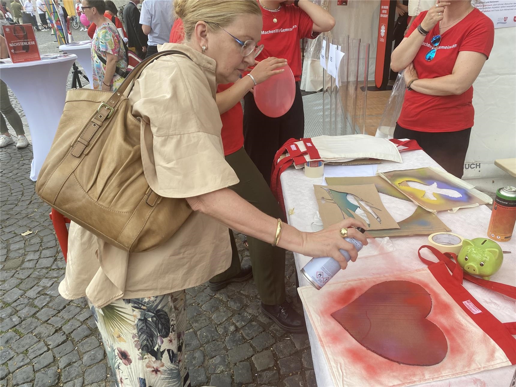 Eine Dame sprüht ein Herz auf eine Tasche (Foto: DiCV Mainz, Referat Kommunikation)