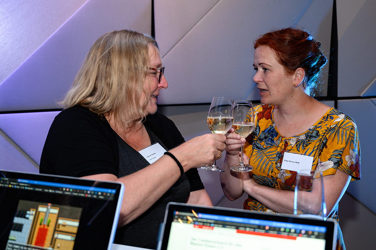Sabine Depew und Katja Dörner stehen zusammen und stoßen mit ihren Weingläsern an (Charles Yunck)