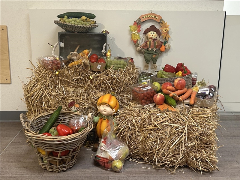 Auf zwei Strohballen liegt verschiedenes Obst und Gemüse und andere herbstliche Dekoration.