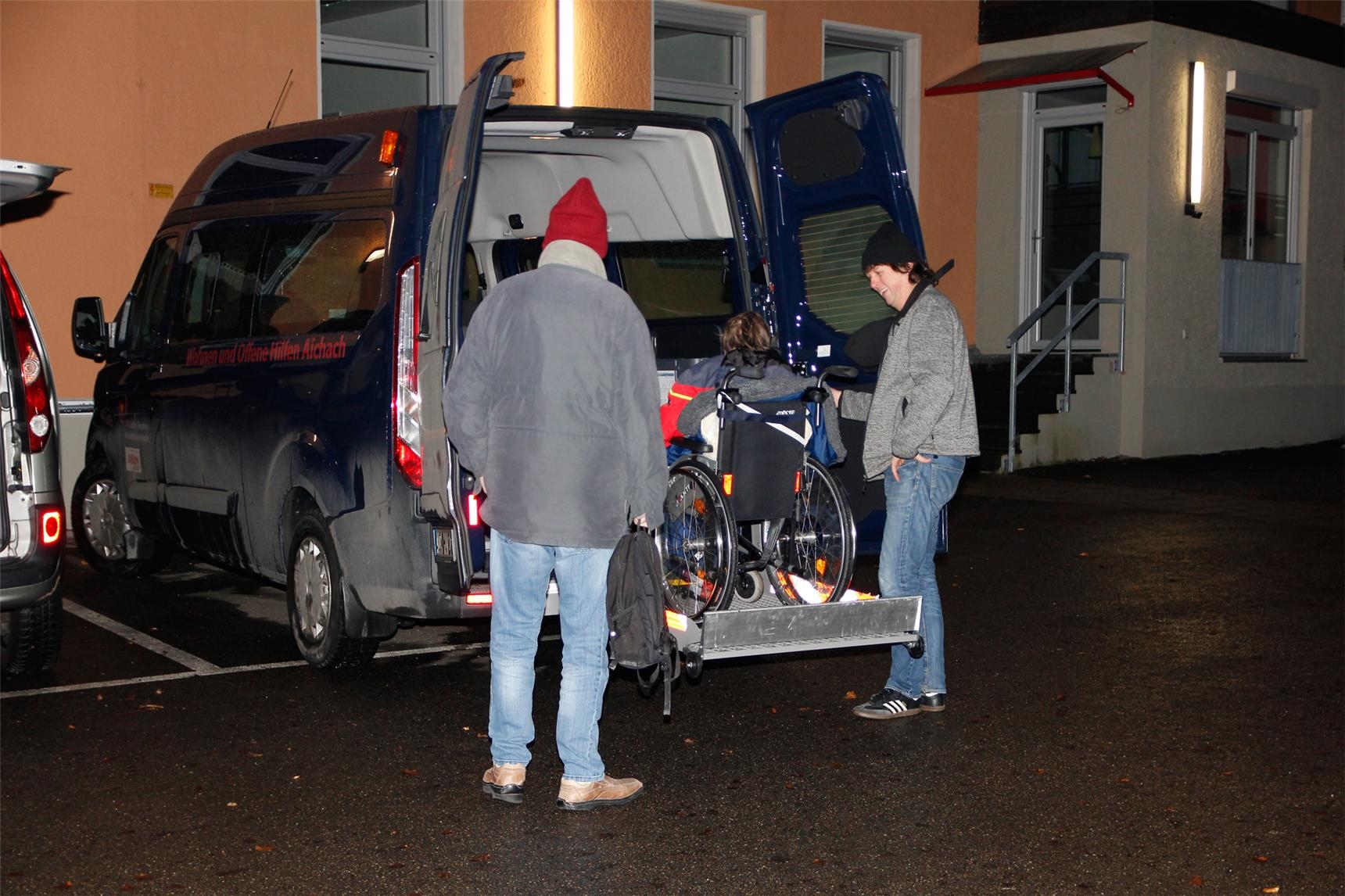 Robert Sanktjohanser, Fachdienstleiter im Ulrichsheim, hilft einer Rollstuhlfahrerin mit der Hebebühne des Fahrzeugs sicher in den Kleinbus. (Bernhard Gattner)
