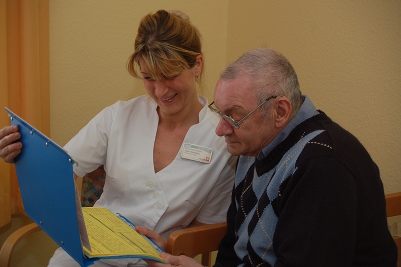 Eine Pflegekraft bespricht mit einem Bewohner die Pflegeplanung (Annette Bomba)