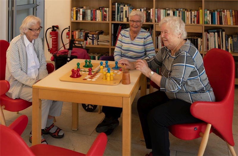 Drei Seniorinnen sitzen am Tisch und spielen Mensch ärgerd Dich nicht