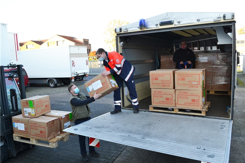 Das Foto zeigt drei Männer, die Kisten in einen LKW verladen.