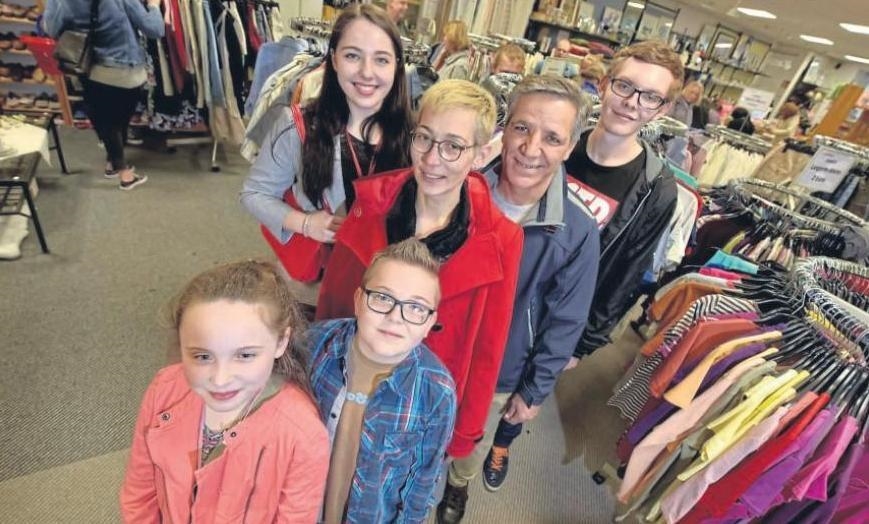 Zwei Erwachsene und vier Kinder stehen im Verkaufsraum zwischen Kleiderständern (WA Rother)