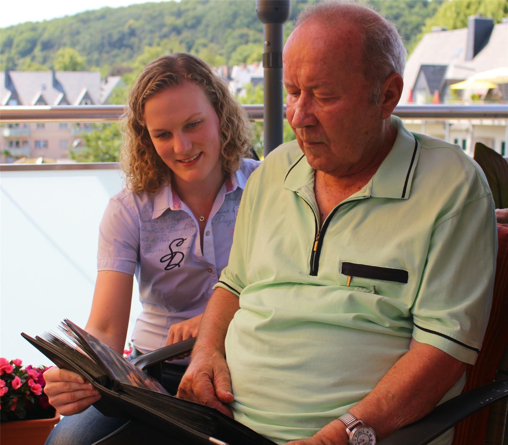 Senior und Pflegerin blättern in Broschüre auf der Terrasse (Foto: Marco Wagner)