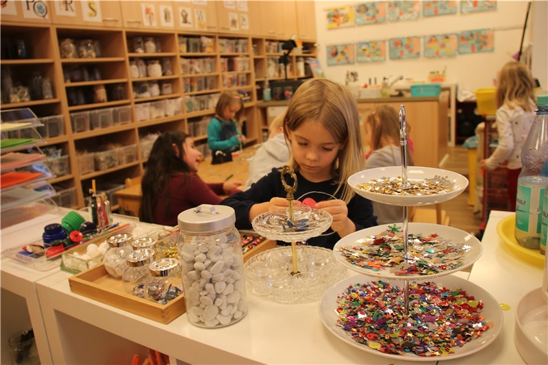 Das Foto zeigt ein Kinder in einem Kindergarten, das konznetriert mit Perlen spielt.