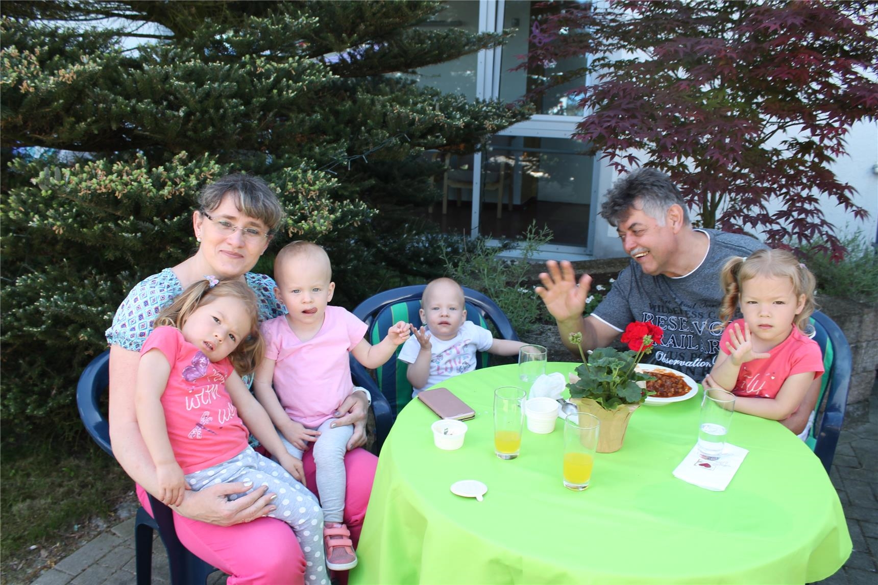 Familie mit vier Kindern sitzen am Tisch im Garten (St. Vinzenz-Vorsterhausen)