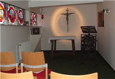 Ein Blick in den Andachtsraum mit Altar, Kruzifix und bunten Glasfenstern. / Mario Horn