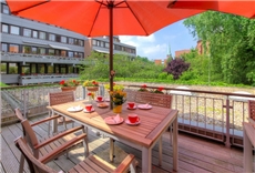 Sitzgruppe auf der Terrasse mit rotem Sonnenschirm und Blick auf die Stadt Lübeck / Uwe Freitag