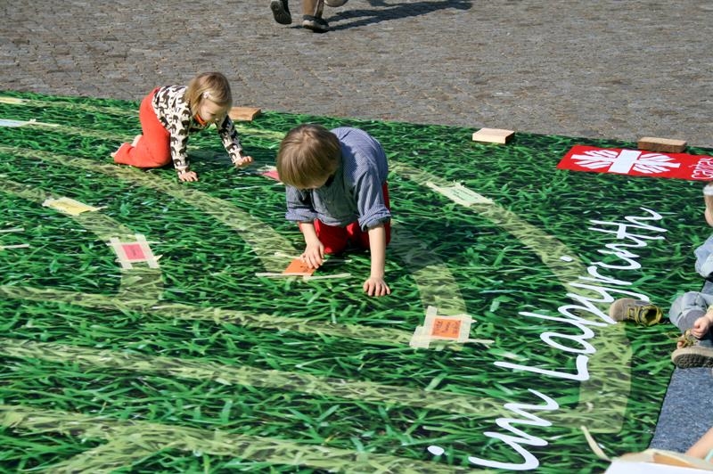 Kinder krabbeln über eine Matte, auf der ein Labyrinth abgebildet ist 