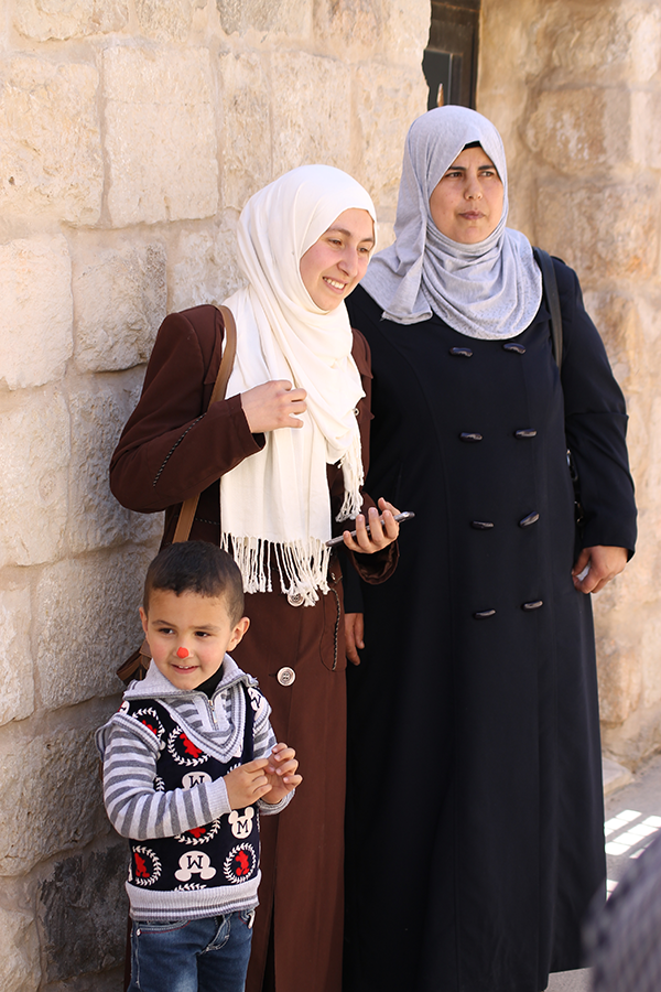 Zwei Frauen mit Kopftuch stehen mit einem Jungen vor einer hellen Steinmauer (Markus Harmann)