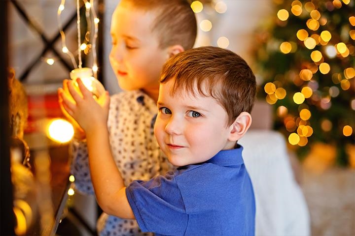 Dank ihrer Spende sitzt ein Junge vor einem beleuchteten Weihnachtsbaum. 