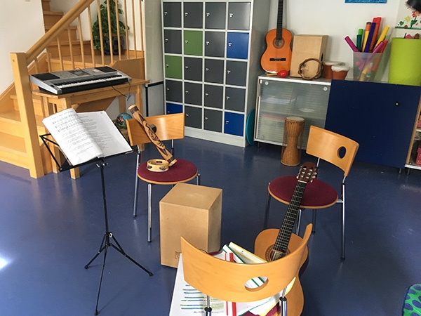 Musikbereich eines größeren Raums, mit Gitarren, zwei Cajón-Boxen, Regenröhre, Schellenringen, Djembe-Trommel und einem Keyboard (Caritasverband Darmstadt e. V.)