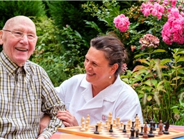 Eine Pflegerin spielt auf der Terrasse der Tagespflege mit einem Senioren Schach / Werner Krüper