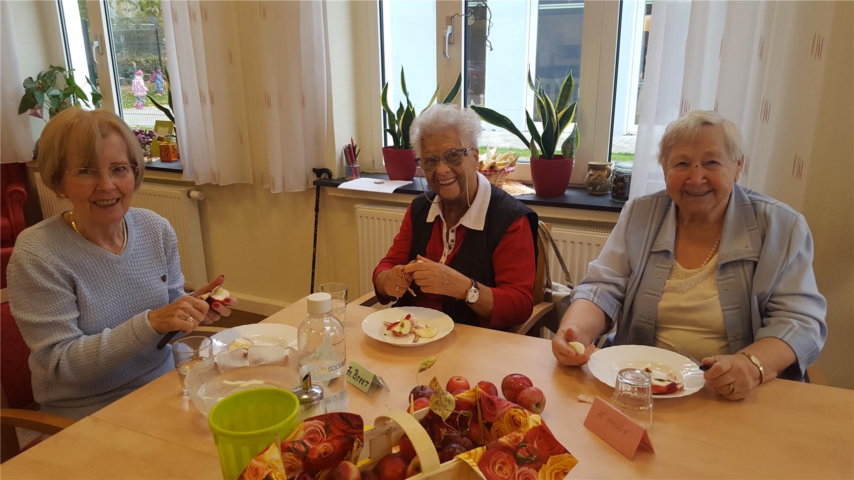 Drei Seniorinnen sitzen am Tisch und schälen Äpfel (Tagespflege St. Rochus)