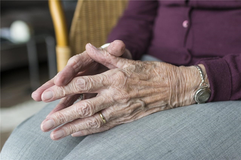 Das Foto zeigt die Hände einer alten Frau, die sie im Schoß faltet.