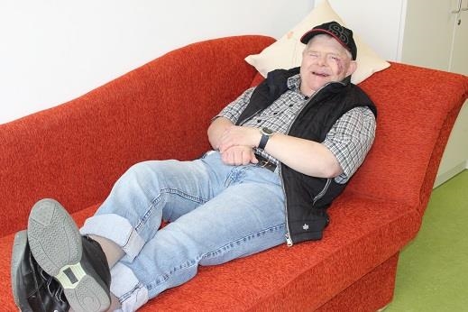 Ein Mann liegt völlig entspannt auf einem Sofa. (Wohnpflegeheim)