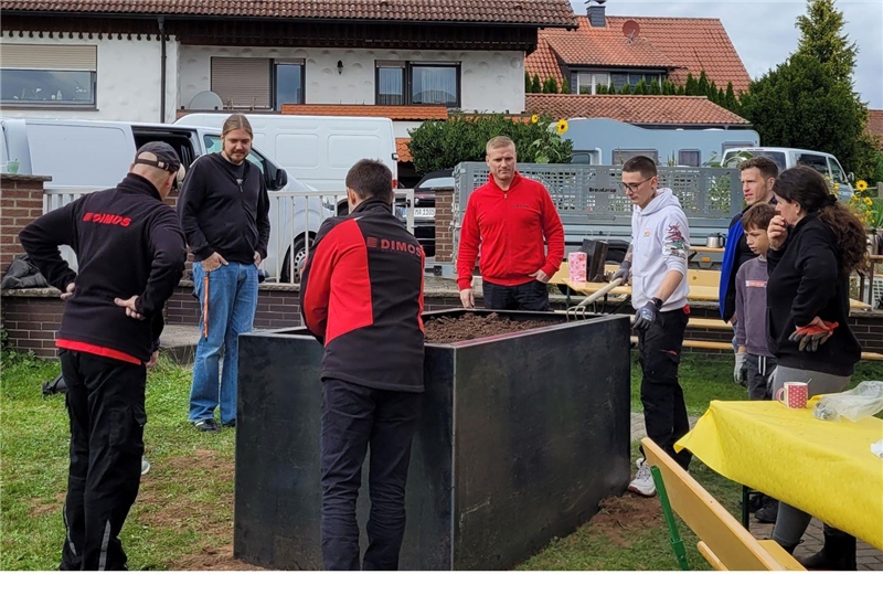 mehrere Personen neben einem aufgebauten Hochbeet