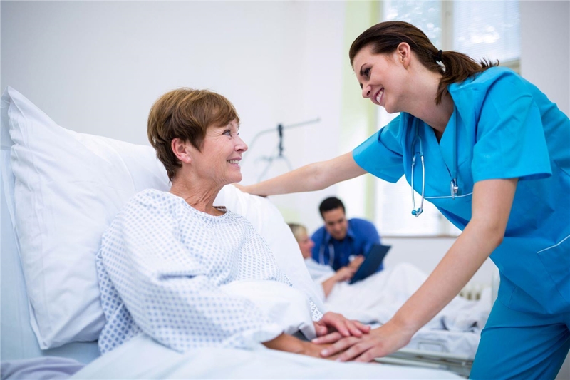 Krankenschwester beugt sich über Patientin im Bett