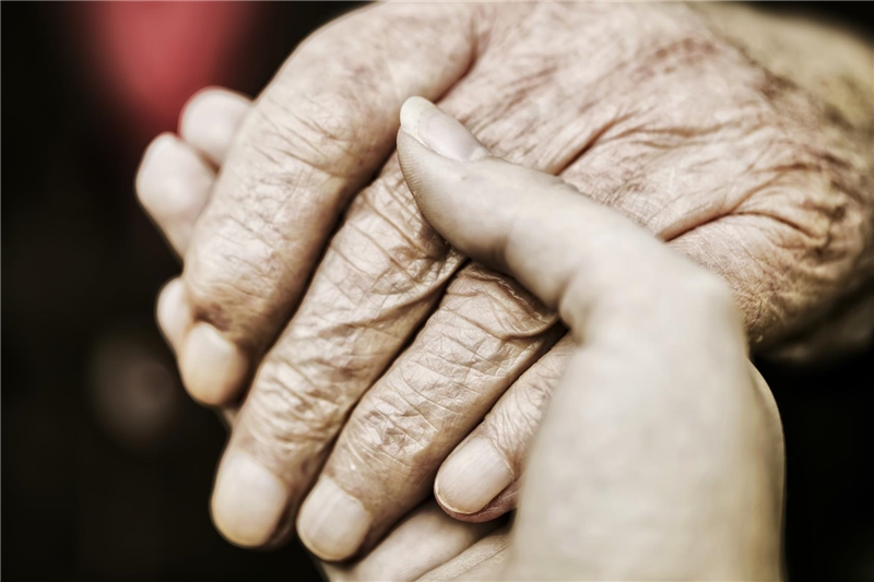 Hand einer Seniorin wird von der Hand einer jungen Frau gehalten 