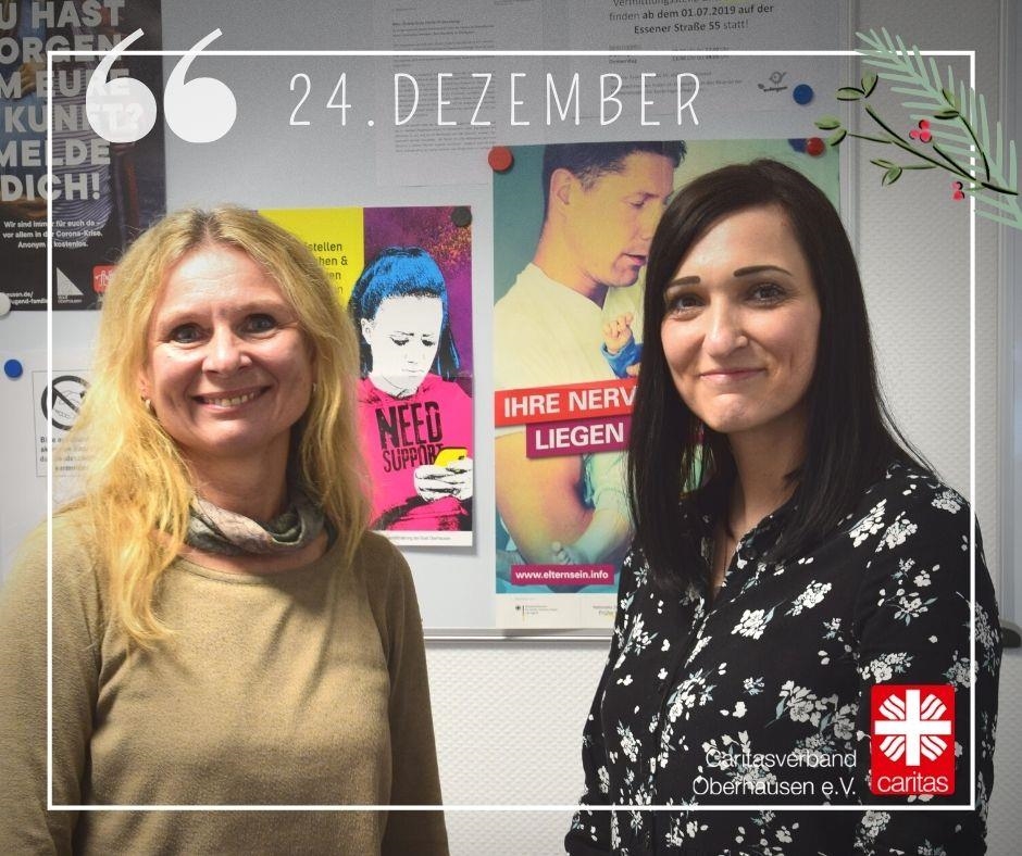 Zwei Frauen von der Schwangerenberatung der Caritas Oberhausen stehen vor einer Magnetwand mit Informationen für Schwangere. 