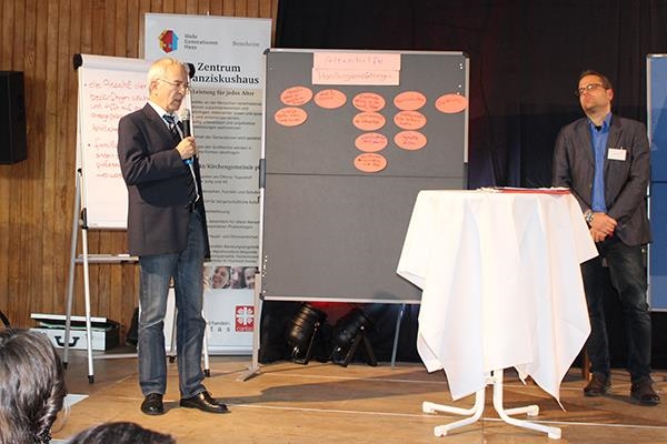 Herr Hans-Peter Kneip mit Mikrofon vor einer Pinnwand mit Zetteln der Arbeitsgruppe (Caritasverband Darmstadt e. V.)