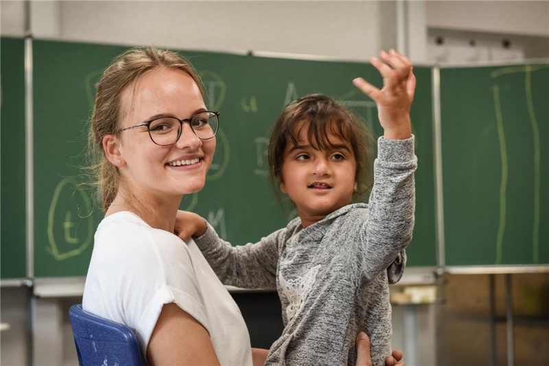 Eine junge Freiwillige mit einem kleinen Mädchen mit Behinderung auf dem Schoß