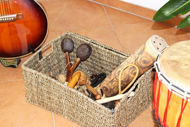 Hölzerne Musikinstrumente in einem Korb neben einer Gitarre und einer Handtrommel (Caritasverband Darmstadt e. V.)