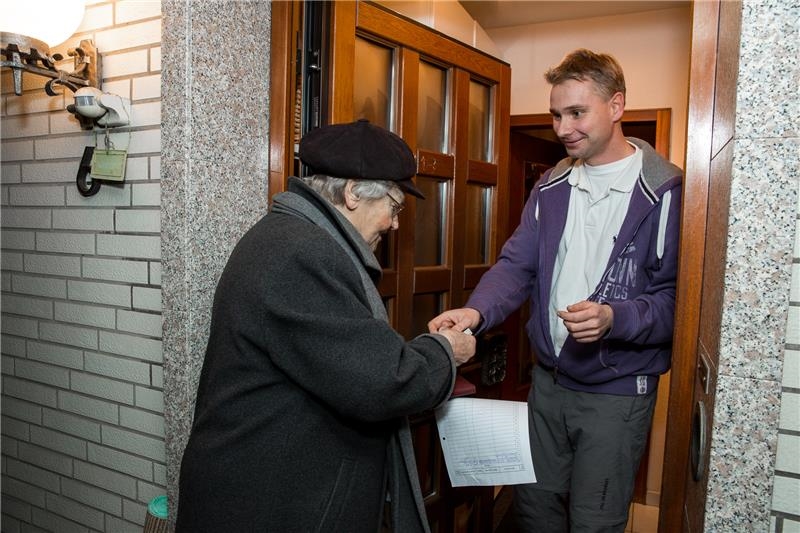 Eine Sammlerin der Caritas wird von einem Spender an der Hustür begrüßt