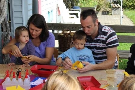 Eine Familie mit zwei Kindern beim Basteln an einem Tisch im Freien. (Cordula Bösmüller, Kita St.Elisabeth Großheubach)