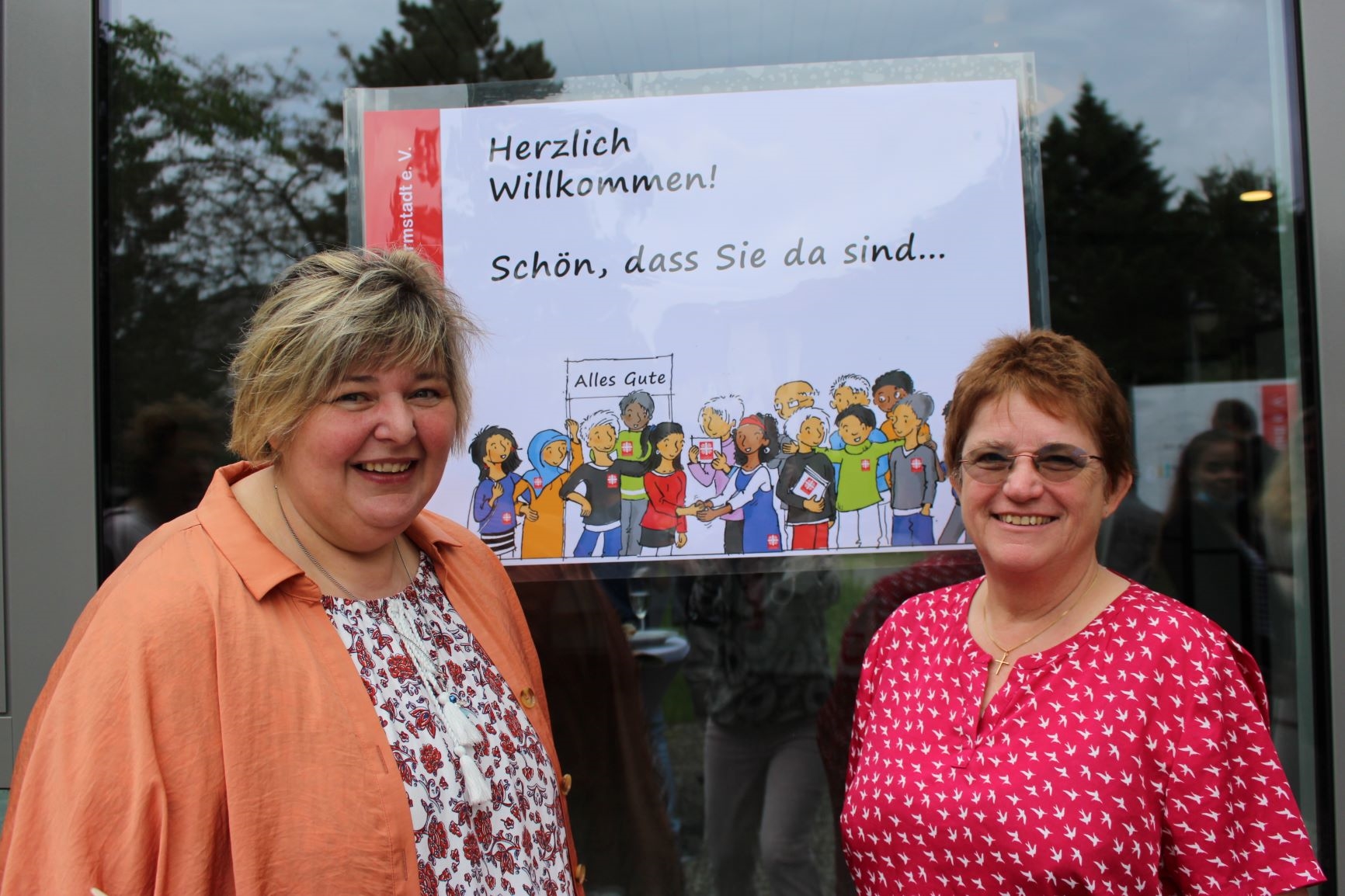 Zwei Frauen vor einem Plakat (Caritasverband Darmstadt e. V.)