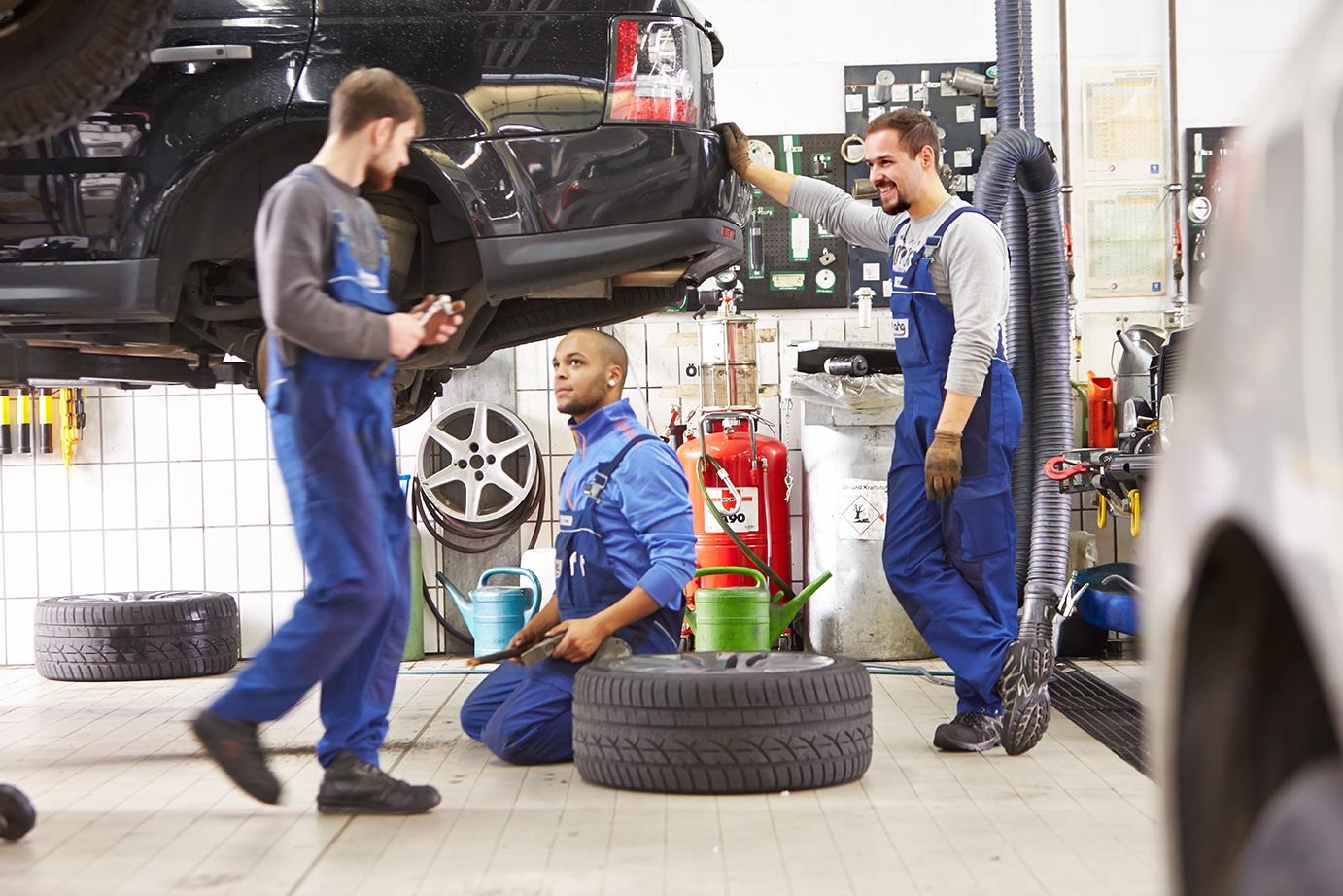 Drei Männer arbeiten in einer Autowerkstatt.