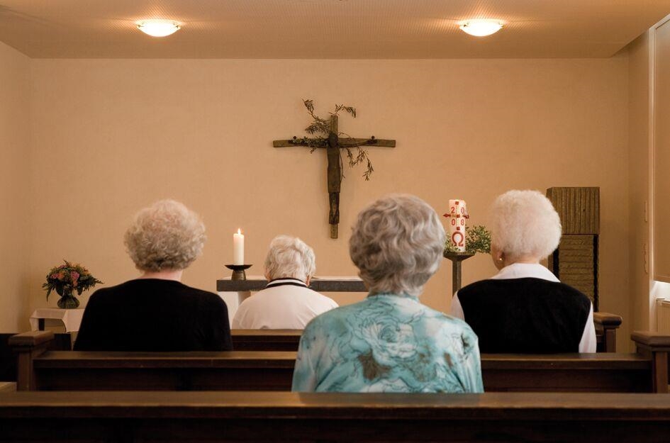 Bewohner sitzen in der Kapelle und beten 