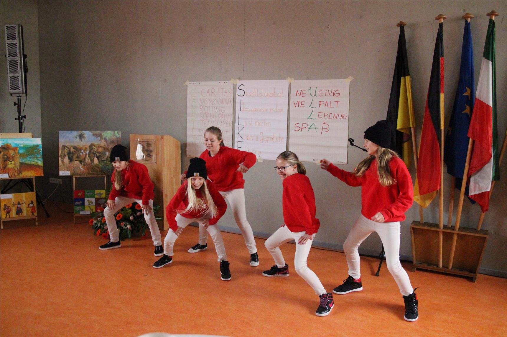 Tanzaufführung im Jugend- und Stadtteilhaus Schicksbaum, Innenansicht mit mehreren jungen Tänzerinnen in Aktion, alle haben rote Pullover an 