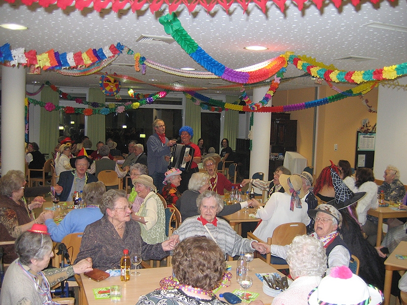 Bewohnerinnen und Bewohner feiern ausgelassen Fasching im großen Speisesaal. 