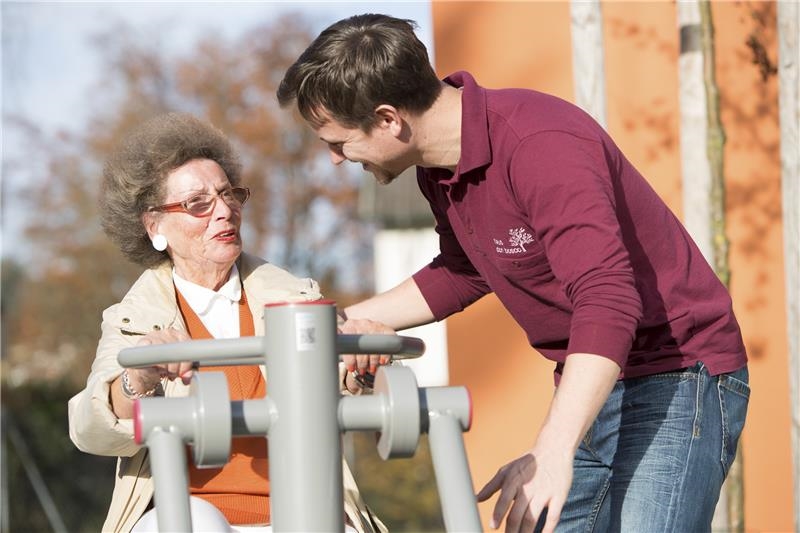 Seniorin mit Pfleger am Sportgerät draußen (Quelle: Deutsche Fernsehlotterie)