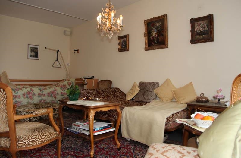 Zimmer mit Bett, Couch, Stühlen und Tisch sowie Bildern an der Wand 