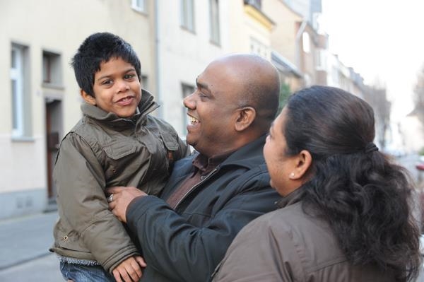 Das Foto zeigt einen Vater mit einem Kind auf dem Arm und danebenstehend die Mutter. (Deutscher Caritasverband/KNA (Harald Oppitz)