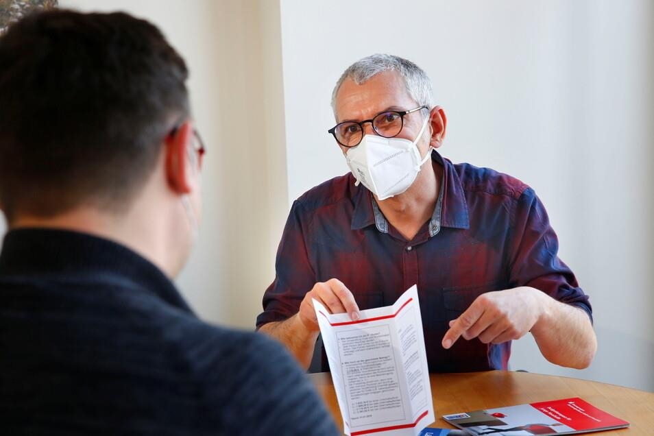 Mann mit Mund-Nasen-Schutz hält Formular in der Hand