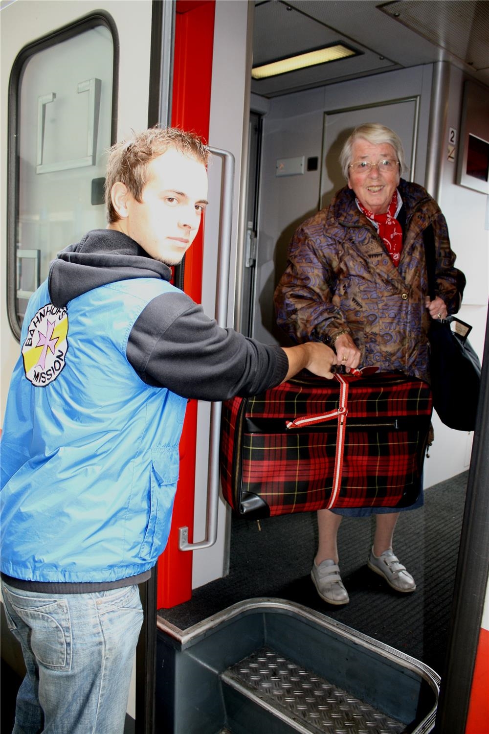 Junger Mann begrüßt Reisende am Bahnhof (Foto: Marco Wagner)