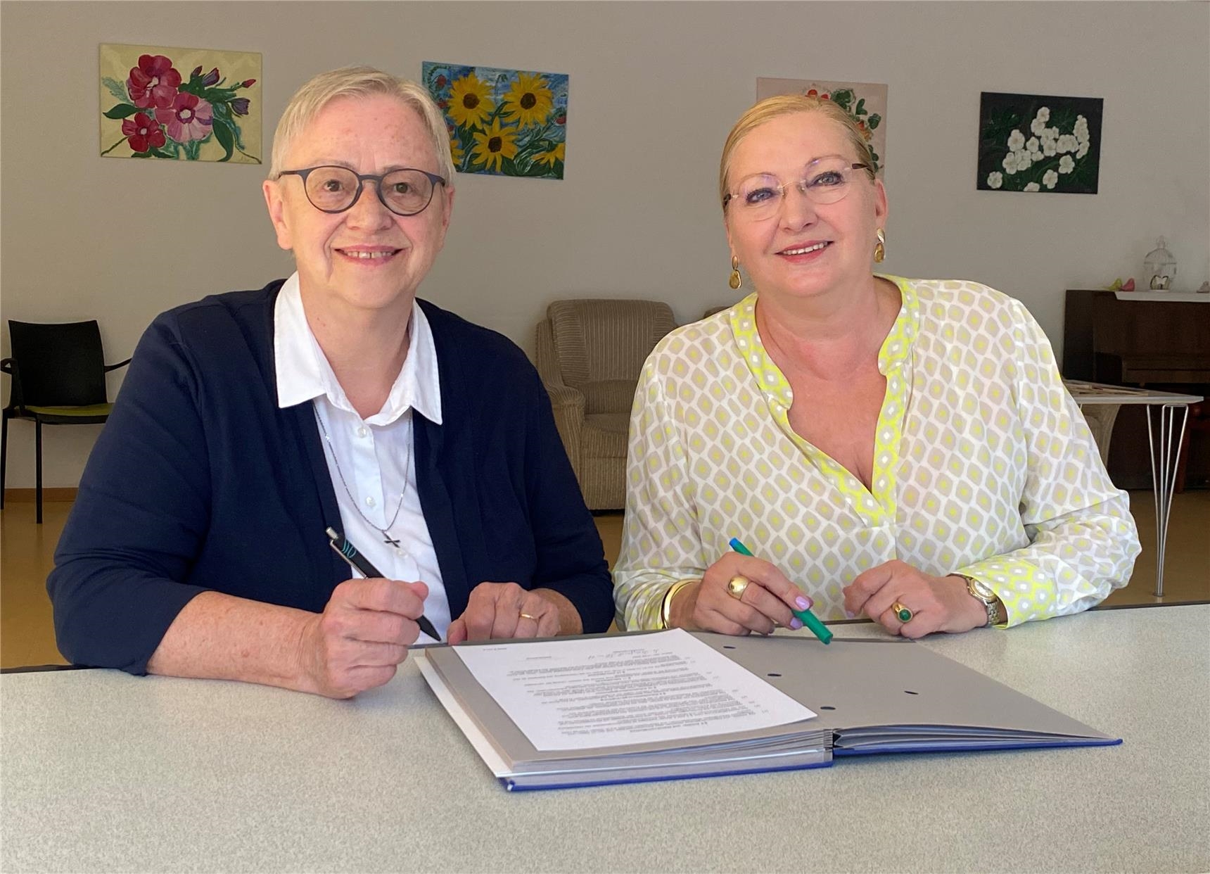 Zwei Freuen sitzen an einem Tisch über einem Vertrag und lächeln in die Kamera (Foto: Caritasverband für die Diözese Mainz e.V.)