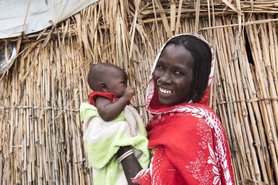 Ein Frau hält ein Baby und lächelt in die Kamera (Michael Stulman, CRS)