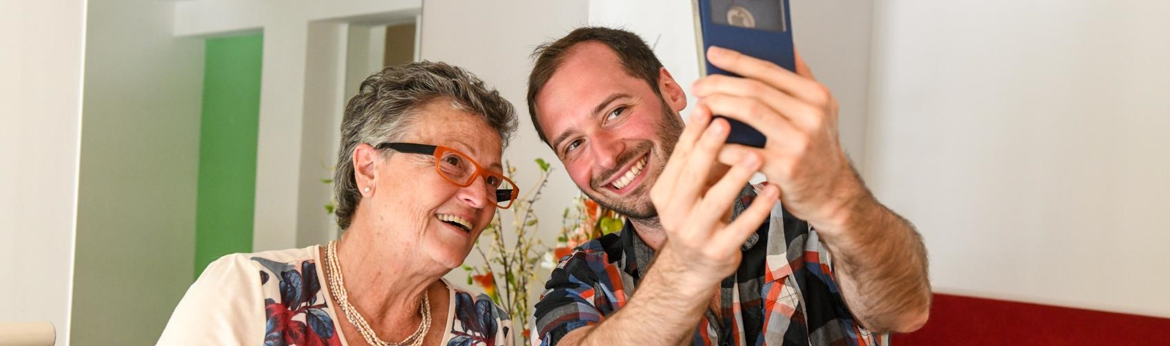 Ein junger Mann und eine ältere Frau machen zusammen ein Selfie