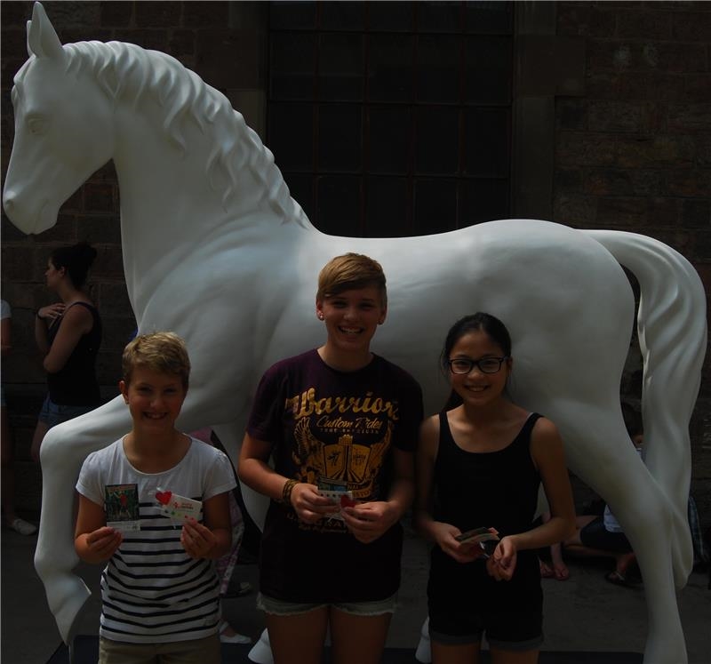 Drei Gewinnerinnen des Malwettbewerbes mit ihren Gutscheinen in der Hand vor dem Pferderohling (Caritas Speyer)