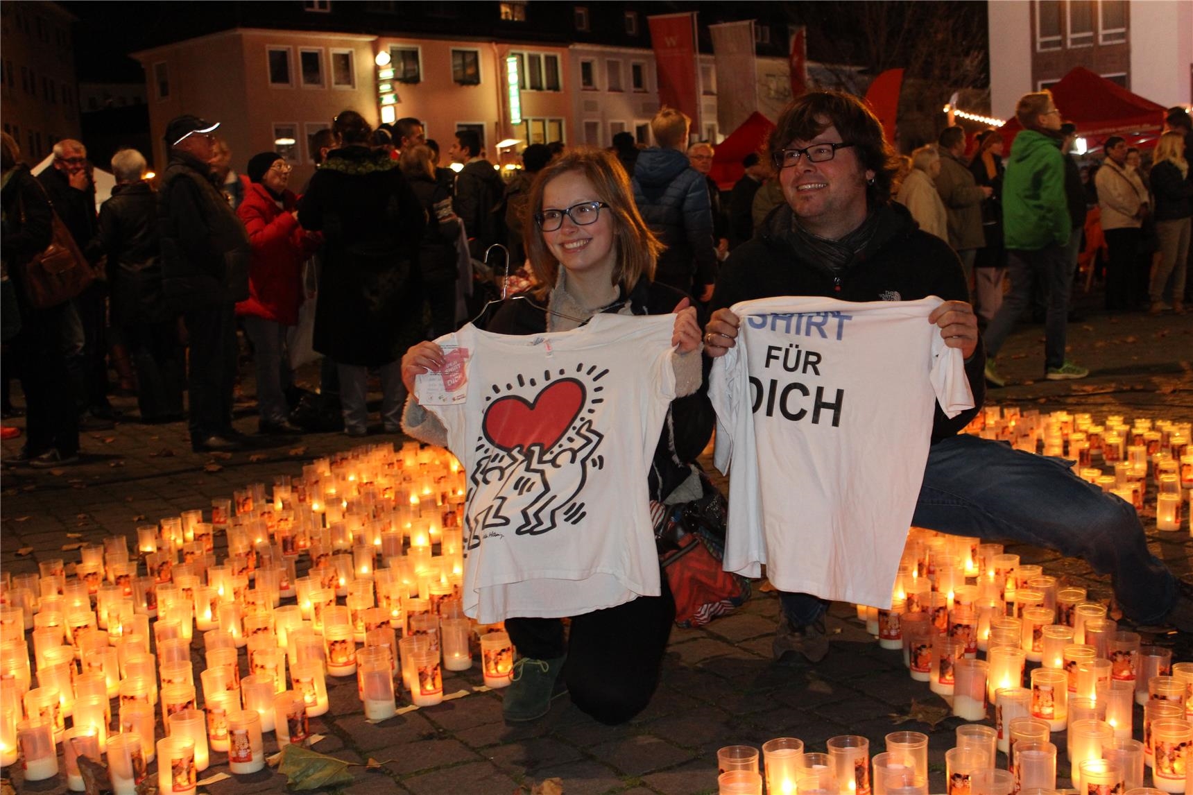 Zwei Menschen mit Shirts zwischen vielen Kerzen (Julia Gaschik)