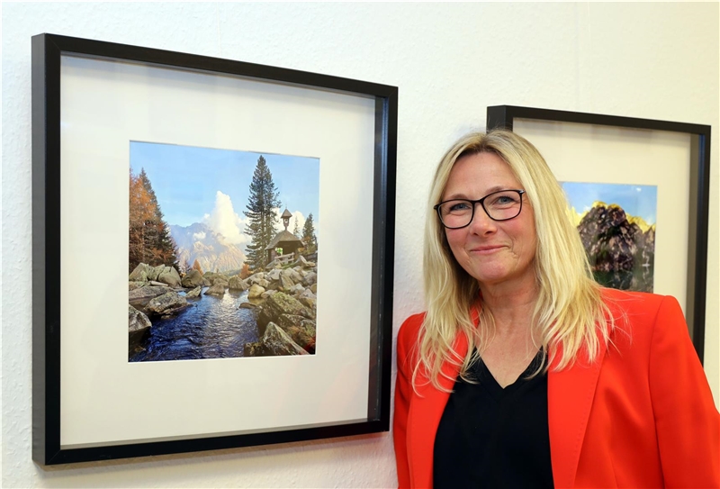 Eine Frau steht neben einem Bild, auf dem ein Fluss zu sehen ist.