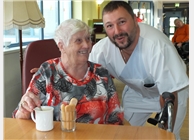 Pfleger Andreas scherzt mit Bewonerin, die sich über die Kaffeepause freut