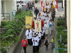 Ein Menschenzug bestehend aus Messdienern mit Fahnen, dem Pfarrer und vielen Teilnehmern führt durch Eschwege. 
