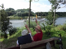 Zwei alte Damen auf einer Bank am Nord-Ostsee-Kanal winken einem vorbeifahrenden Schiff zu. / Mario Horn