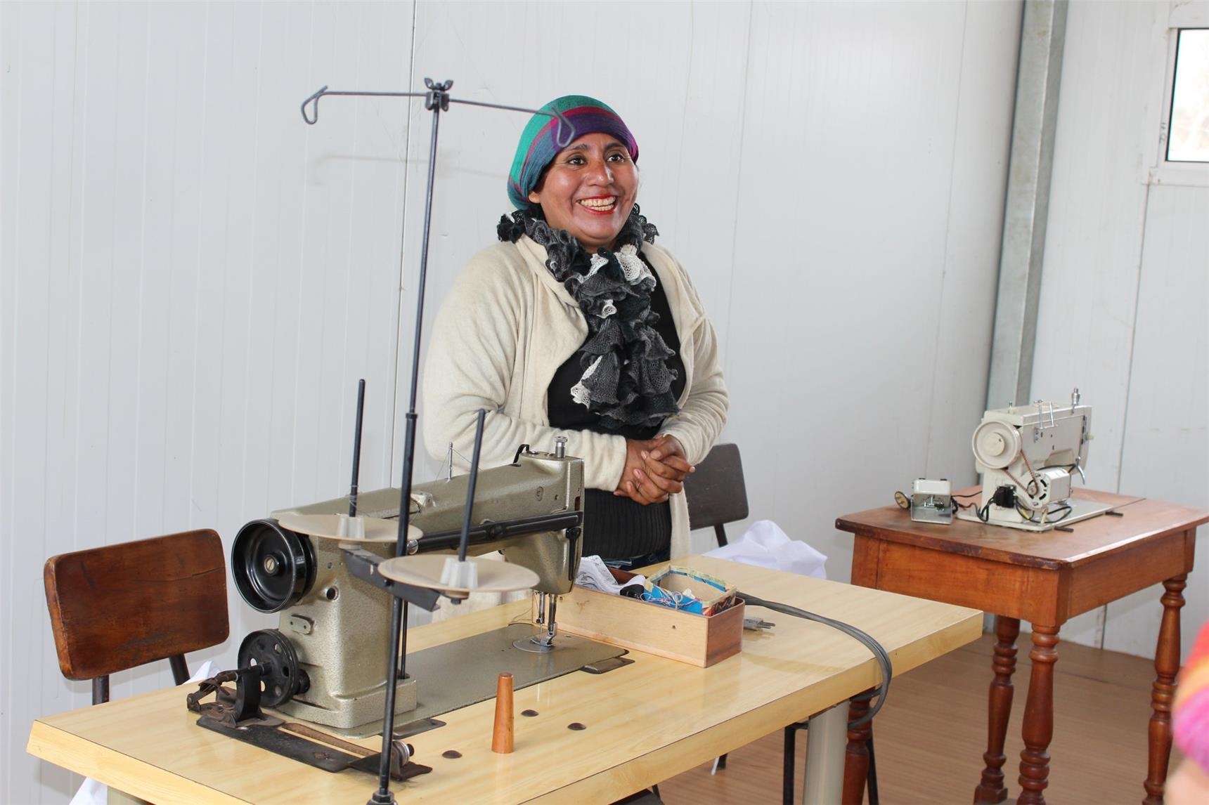 eine peruanische Frau zeigt stolz zwei Nähmaschinen (Foto: Caritas International)